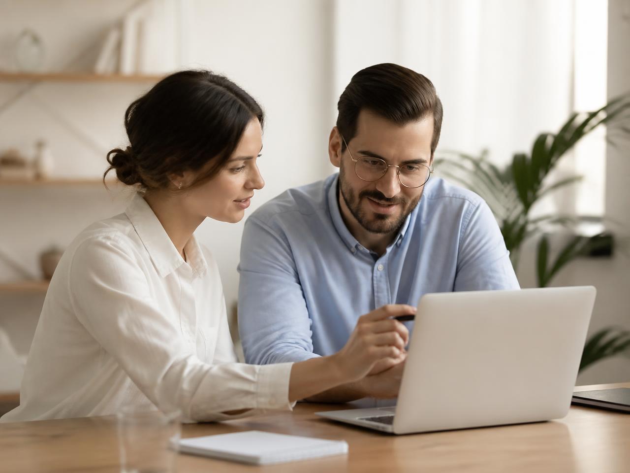 Two colleagues reviewing AgentiCRM drafts together on a laptop